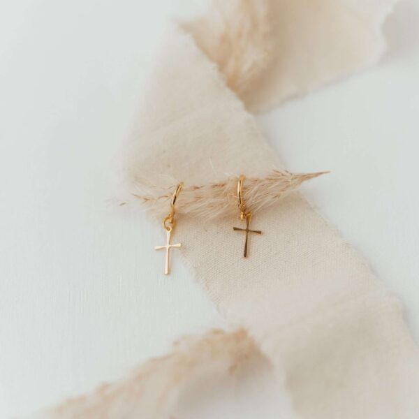 Minimale goldene Kreuz-Ohrringe auf_textilien für christlichen Schmuck Design.