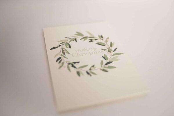 Stilvolle Weihnachtskarte mit grünem Kranz und 'Merry Christmas' Schriftzug.