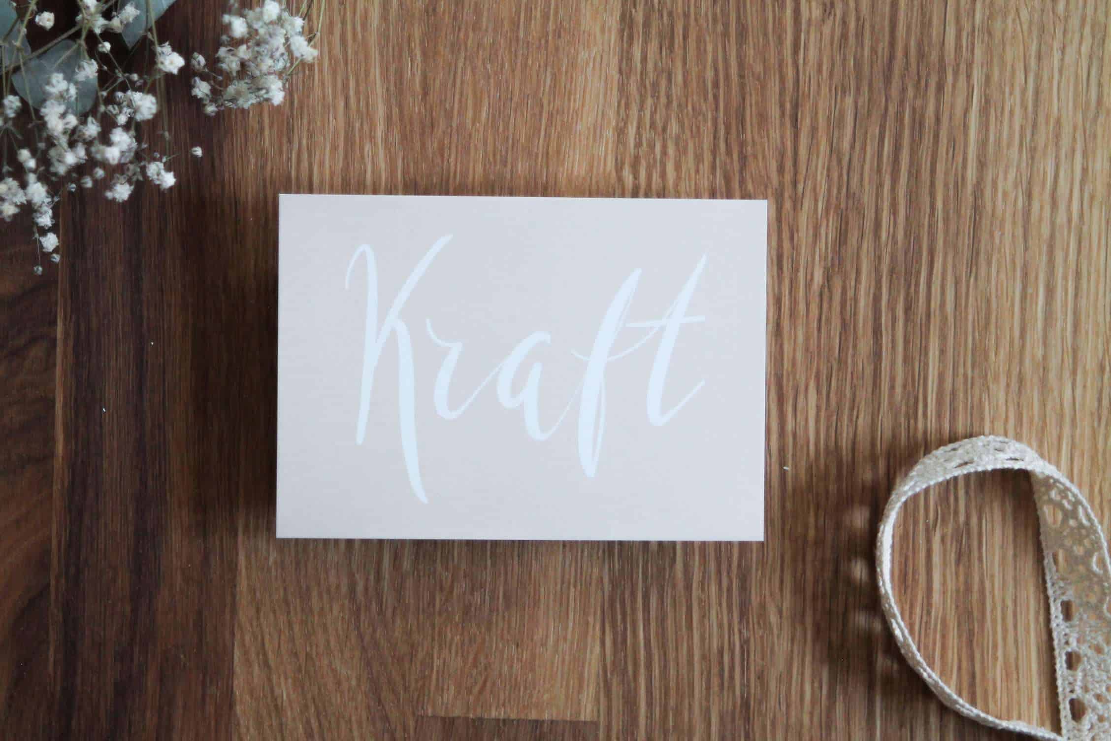 Geschenkkarte mit dem Wort "Kraft" auf holzartigem Hintergrund, christliche Motivation.