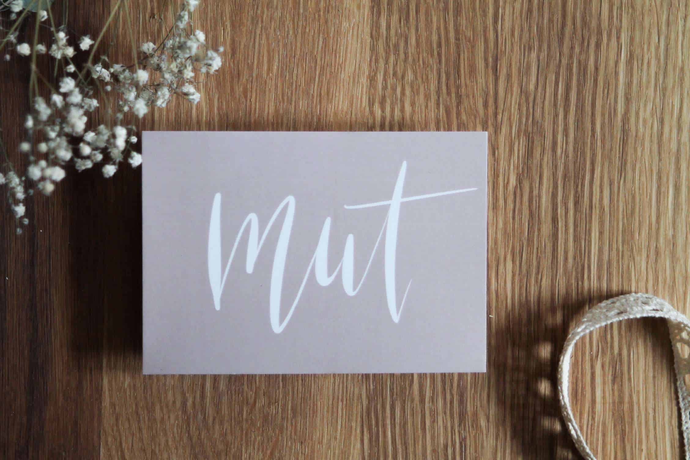 Moderner christlicher Grußkarten-Aufdruck "Mut" auf Holztisch.