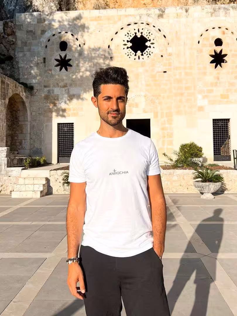 Mann trägt christliches T-Shirt vor historischer Kirche, christliche Mode, Glaube.