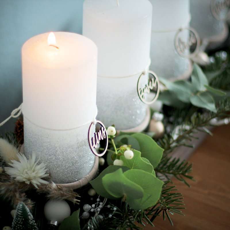 Gemütliche Osterdekoration mit Kerzen und grünen Zweigen.