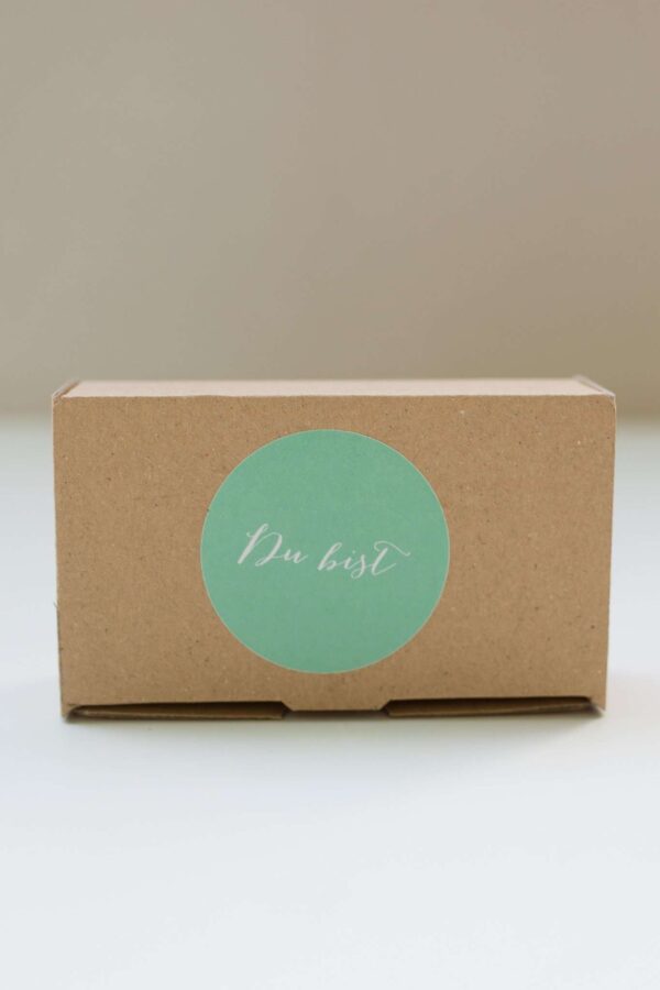 Nachhaltige christliche Geschenkbox mit Grüße-Logo auf Kartonverpackung.