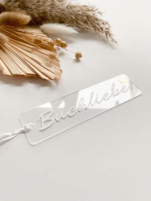 Schriftzug "Bücherliebe" aus Acryl auf weißem Hintergrund mit Trockenblumen und Dekoration.