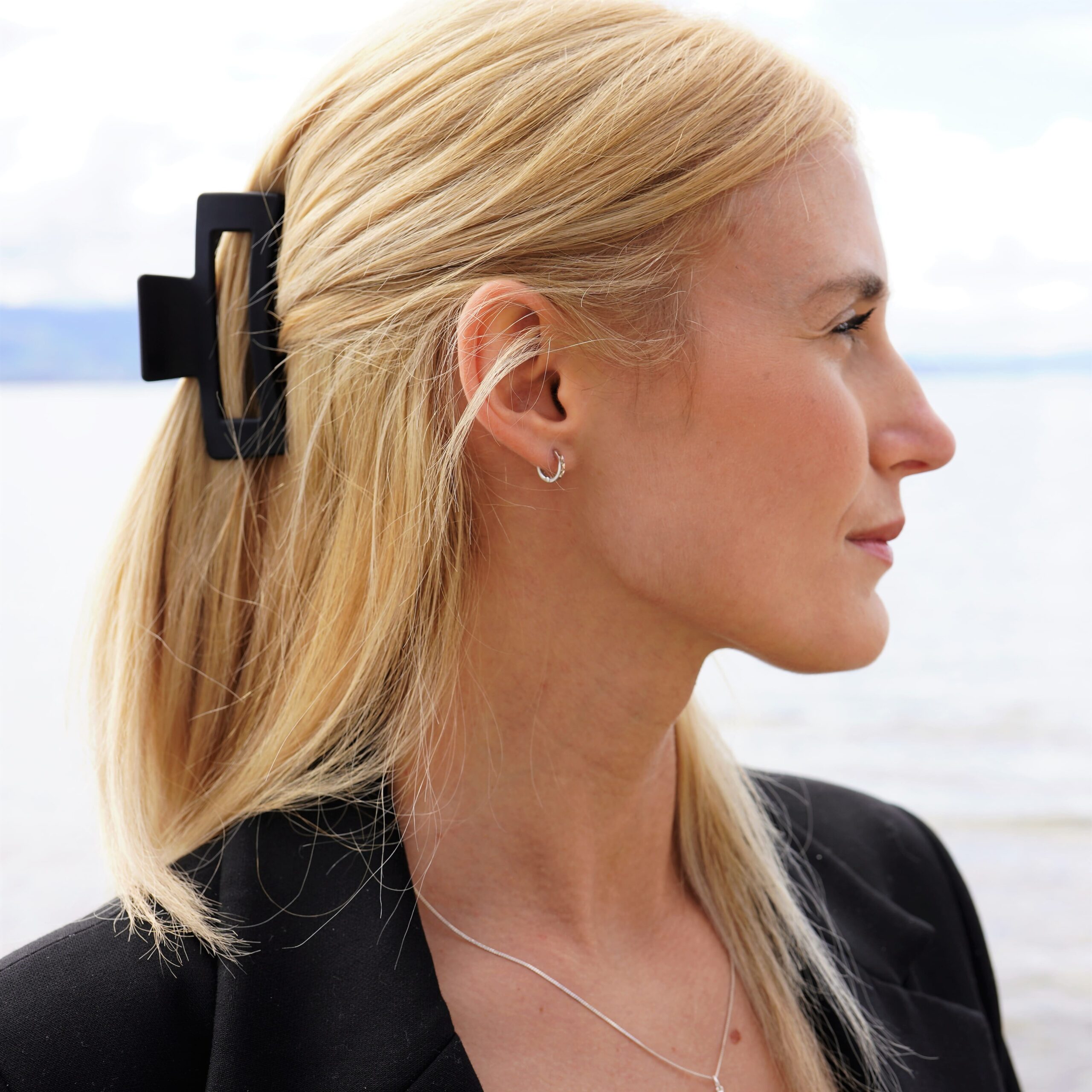 Die christlichen Ohrringe Hoop GLORY von FIRSTGOD und mookho, getragen von einer jungen Frau. Seitliche Nahperspektive.