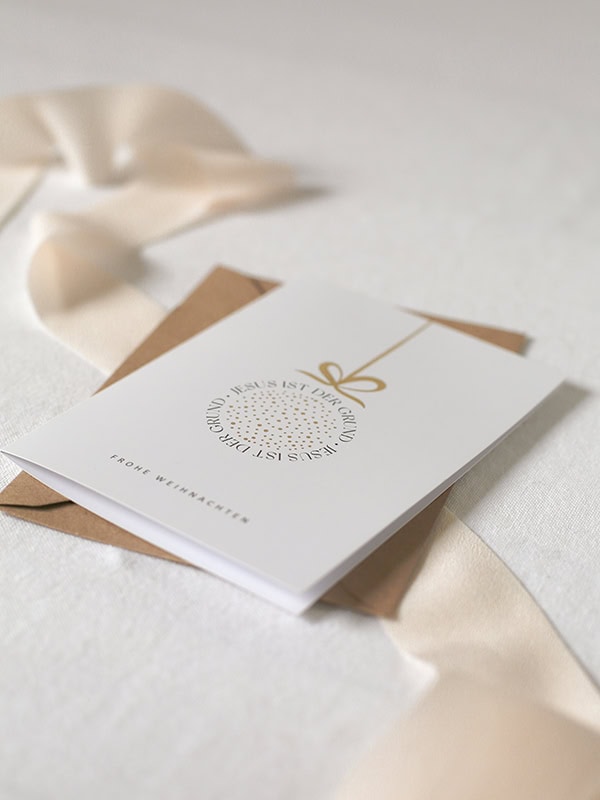 Moderne Weihnachtskarte mit christlichem Gruß und goldener Schleife.