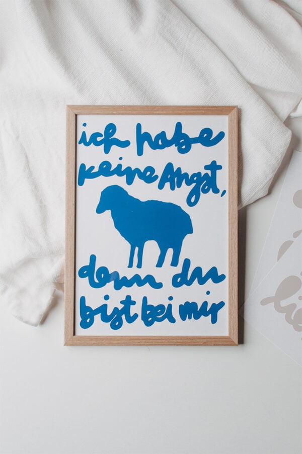 Seitlicher Blick auf christliches Wandbild mit Bibelspruch und Schafmotiv, Flatlay, geistliche Dekoration, Glaube, religiöse Kunst.