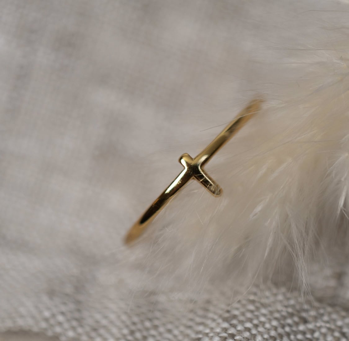 Goldenes Kreuz Schmuck auf weißem Feder-Textil, christliches Symbol, christliche Marken, Mookho.de.