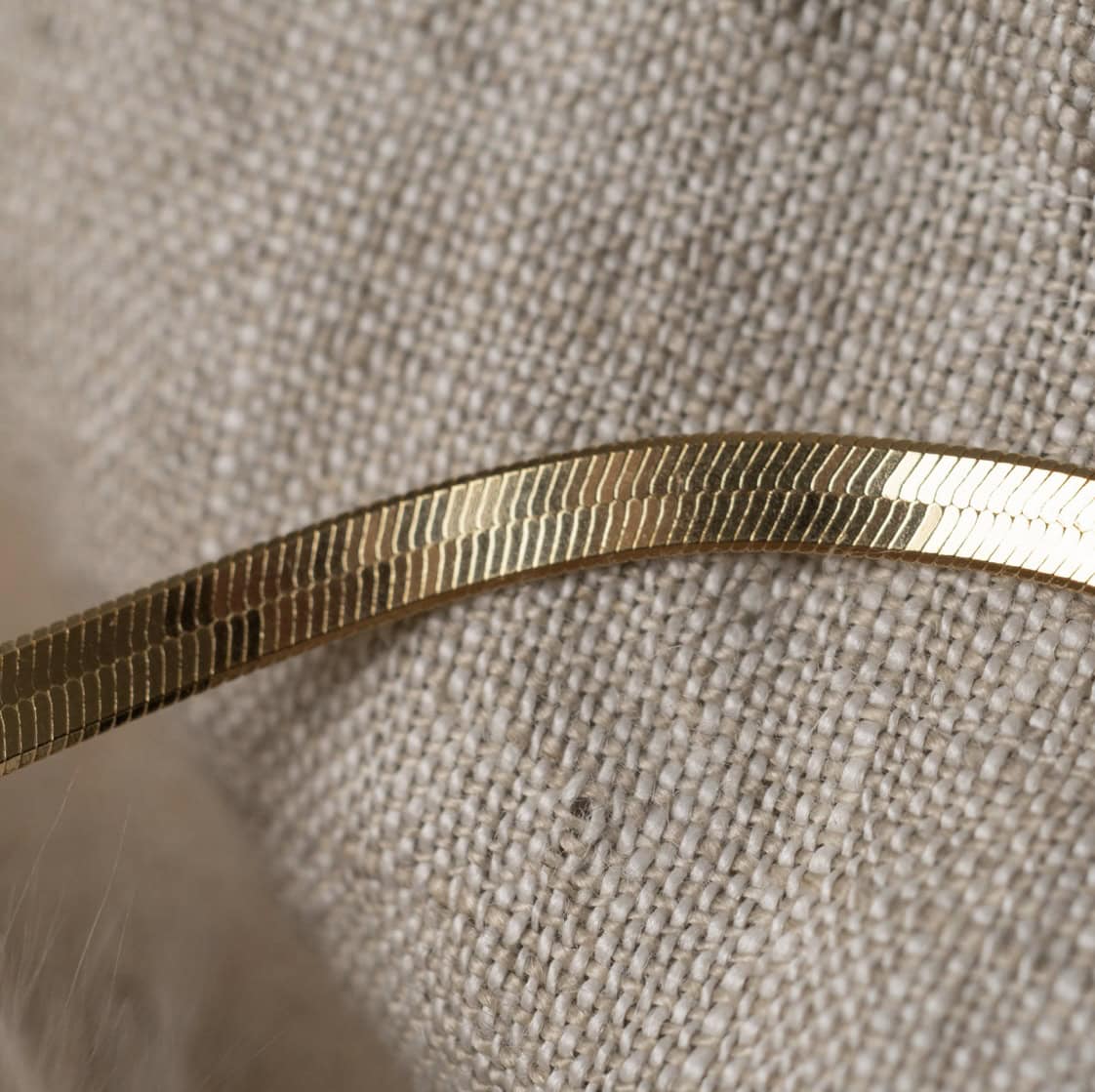 Glänzendes Goldarmband auf beige Stoff, christliche Schmuckkollektion, Bibelvers Schmuck.