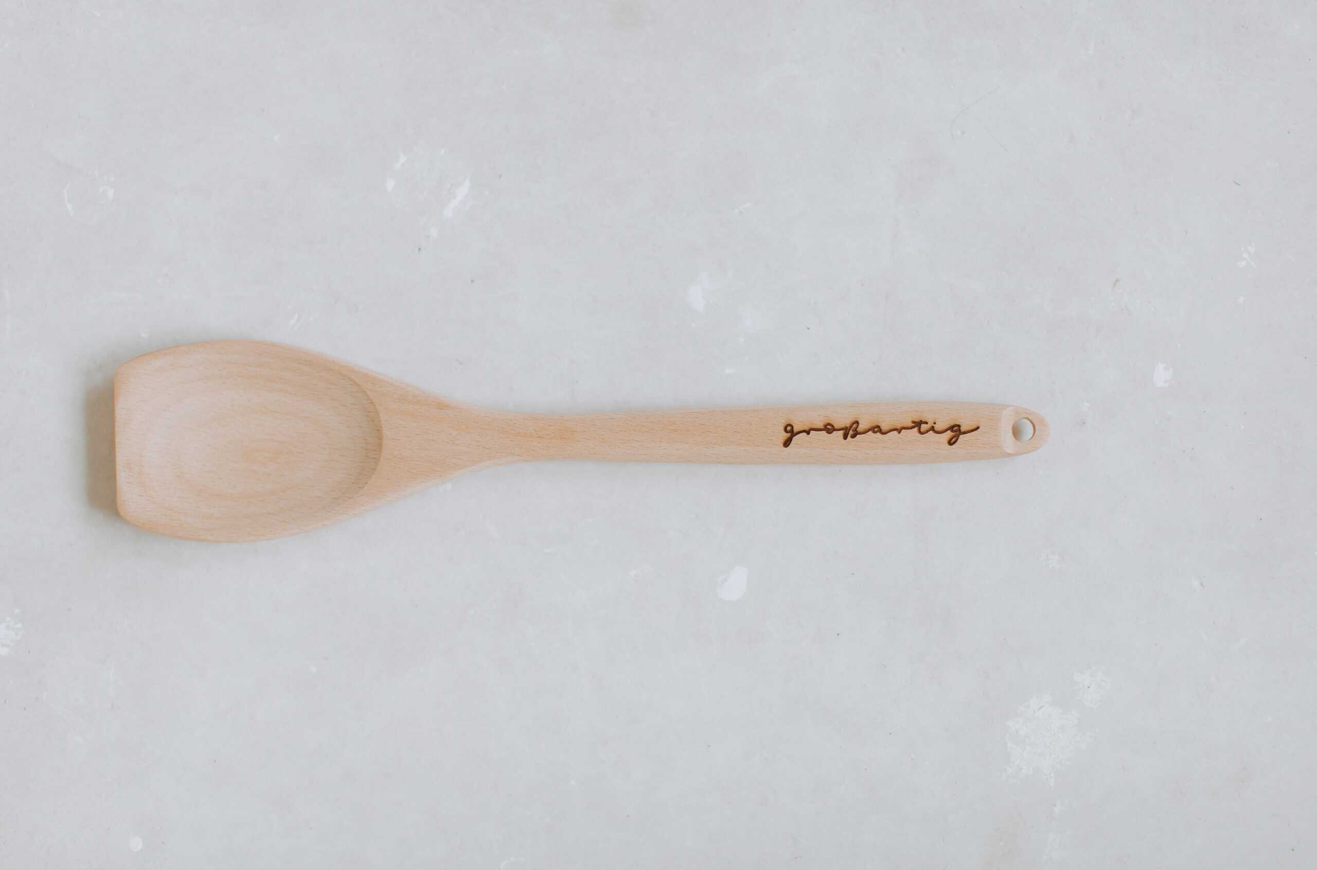 Natur Holz Kochlöffel mit persönliche Gravur auf weißem Hintergrund.