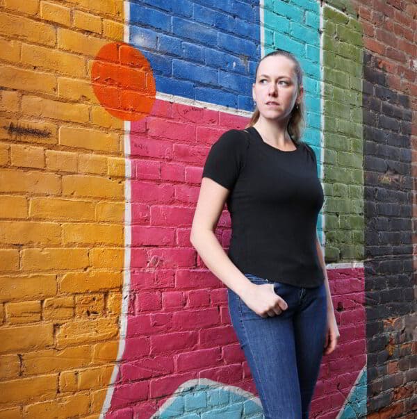 Farbenfrohe Betonwand mit christlichem Graffiti, junge Frau in urbanem Umfeld.