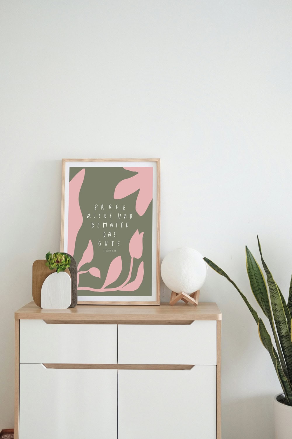 Framed christliches Zitat mit Blumenmotiv an modernem Sideboard im minimalistischen Stil.