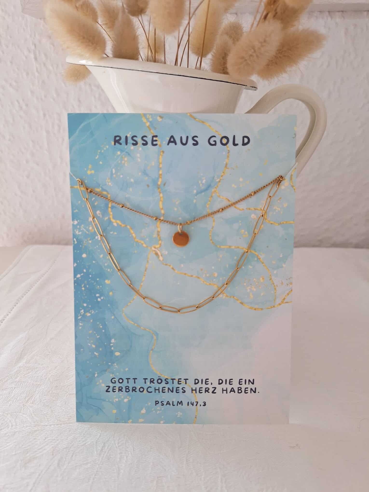 Leuchtendes Goldkettchen auf Gebetskarte mit christlichem Spruch.