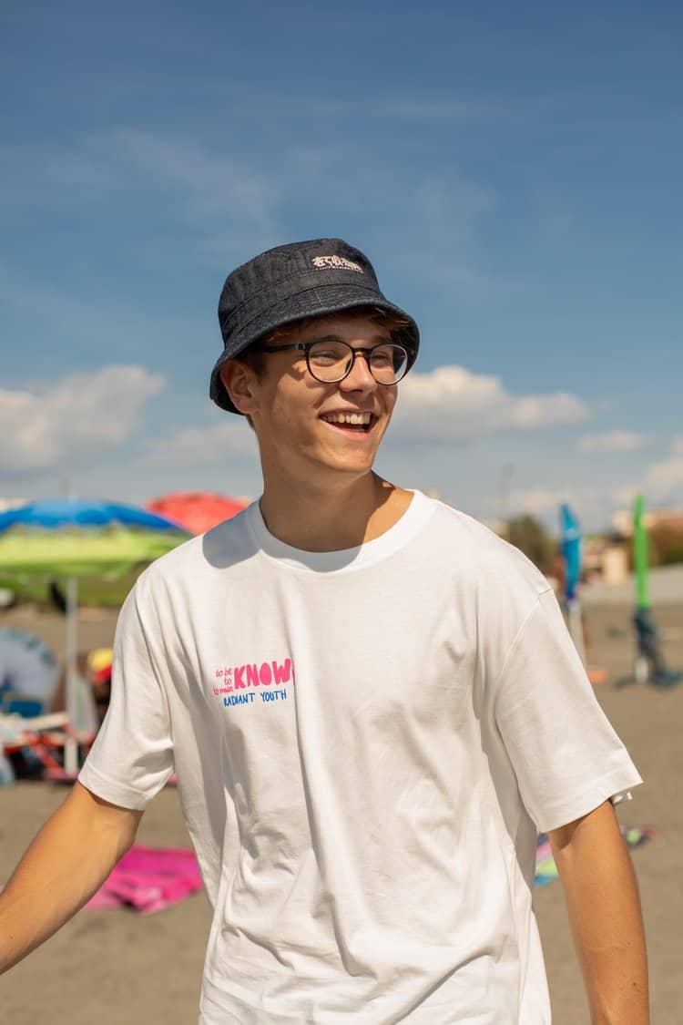 Junge trägt christliches T-Shirt auf dem Strand, moderne religiöse Mode, Jesus Christ.