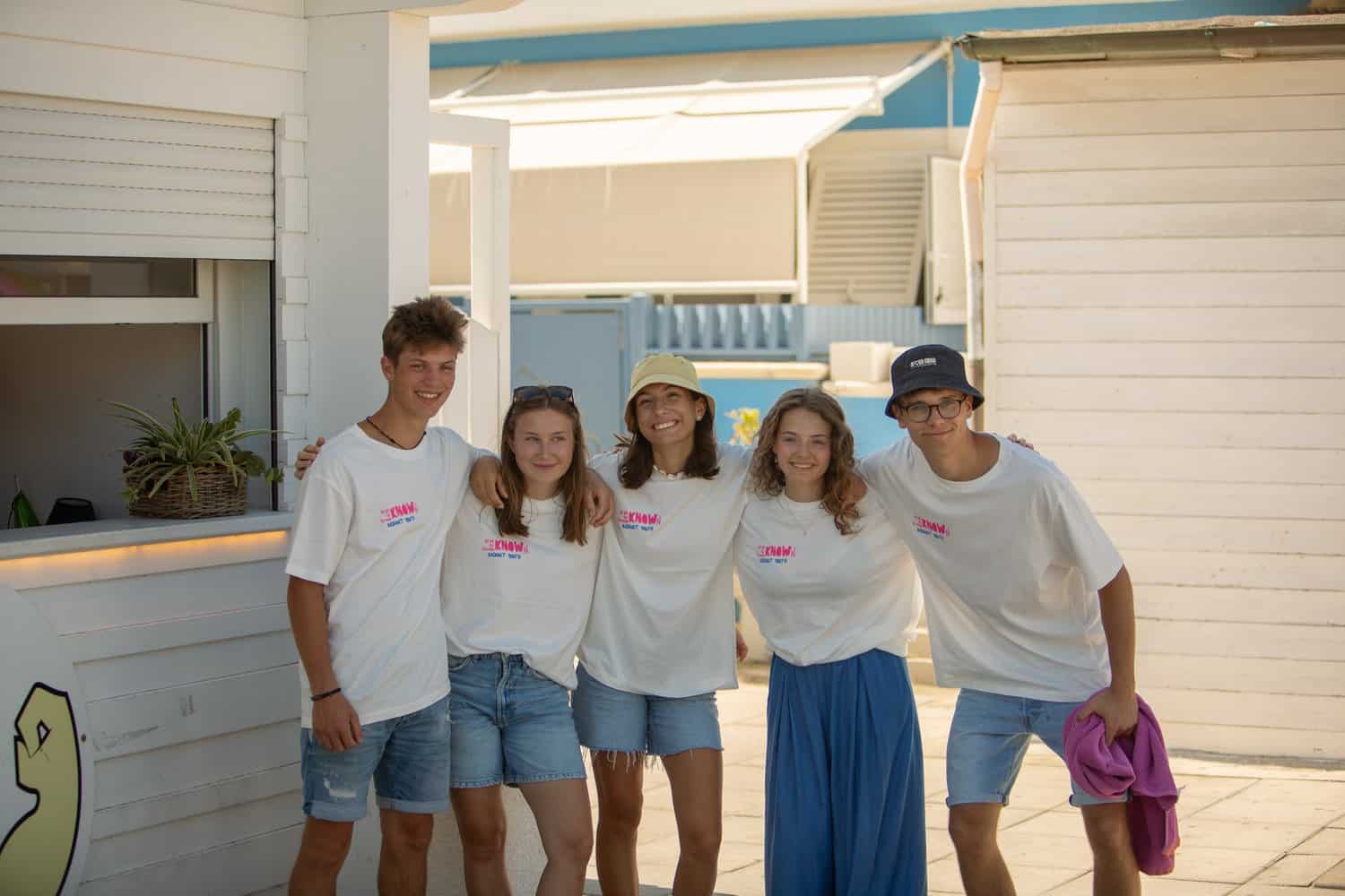 Junge Freunde in T-Shirts mit christlichen Motiven am Strand.