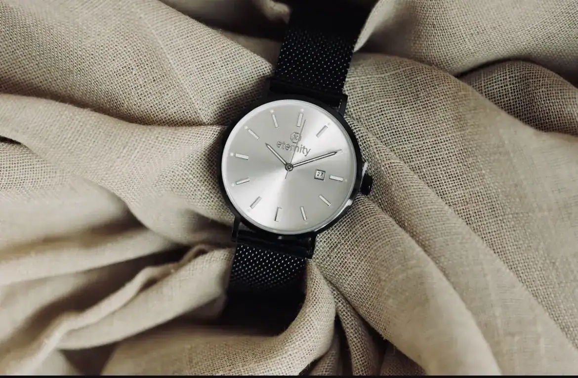 Elegante christliche Armbanduhr mit silbernem Zifferblatt und schwarzem Mesh-Armband.