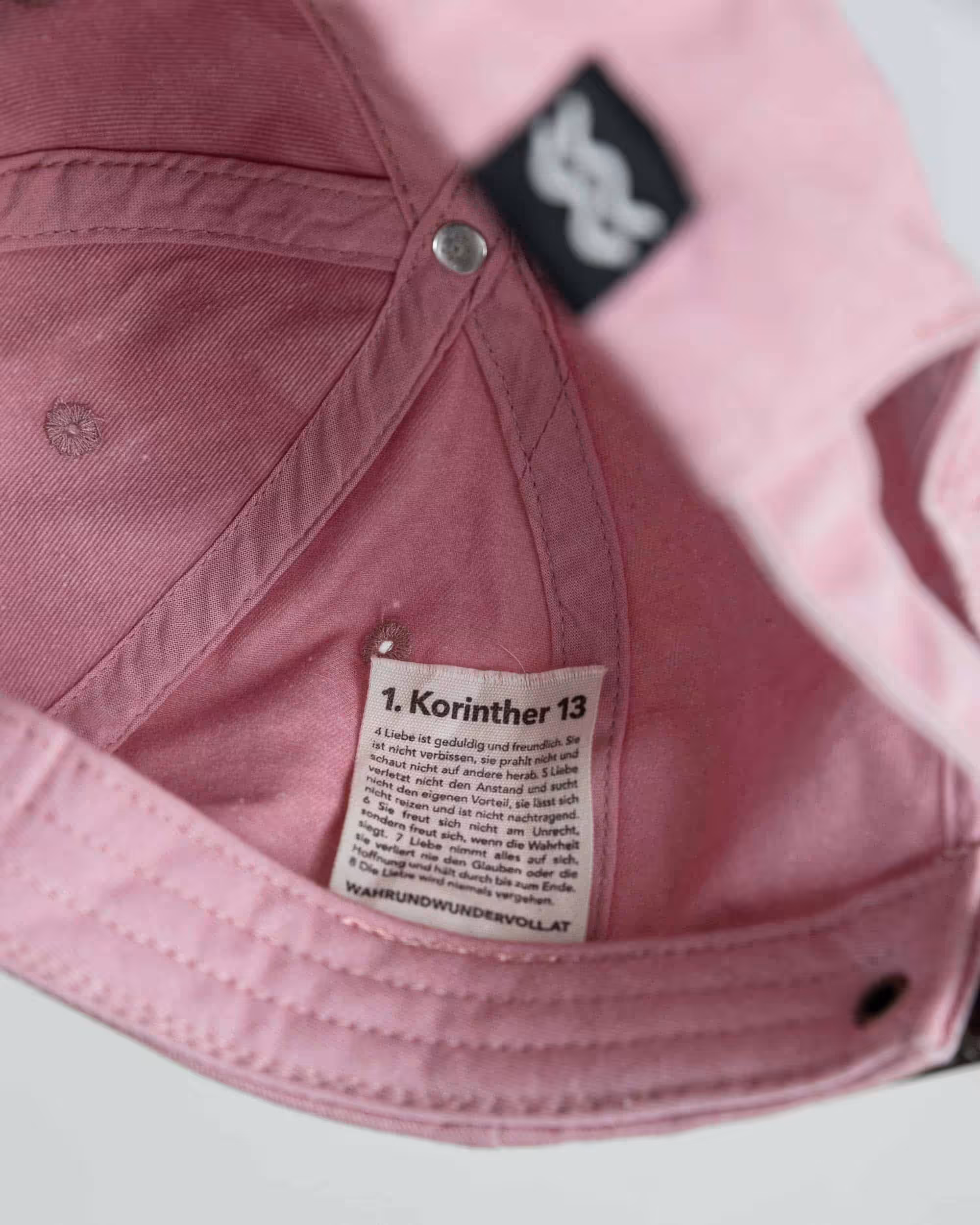 Anderes Bild: Innenansicht eines pinken Christenhutes mit Bibelvers-Label.