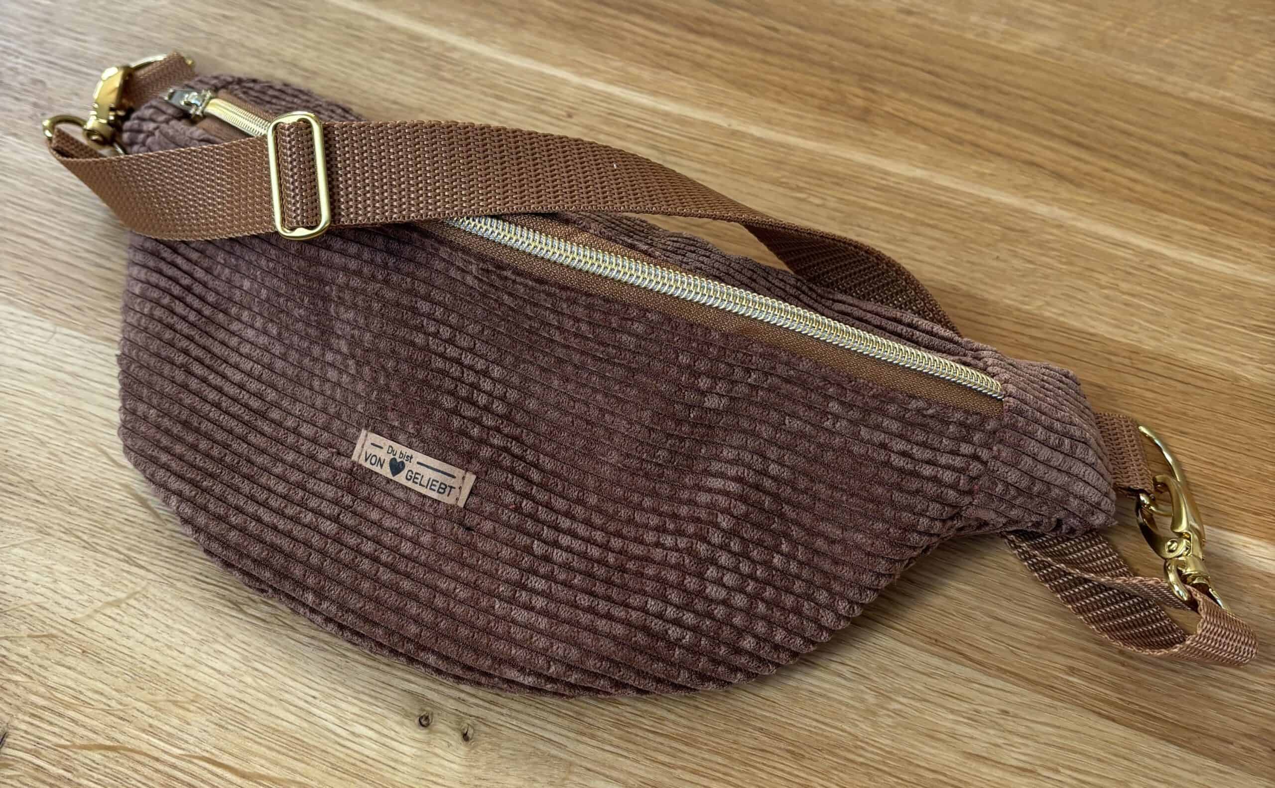 Stylische braune Cord-Umhängetasche mit goldener Zierkette, ideal für christliche Marken.