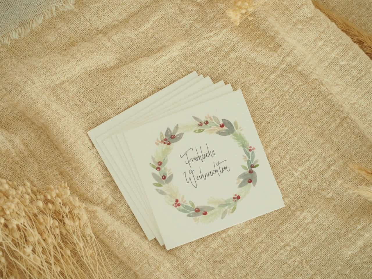 Weihnachtliche Grußkarte mit Tannengrün und "Frohe Weihnachten" Schriftzug.