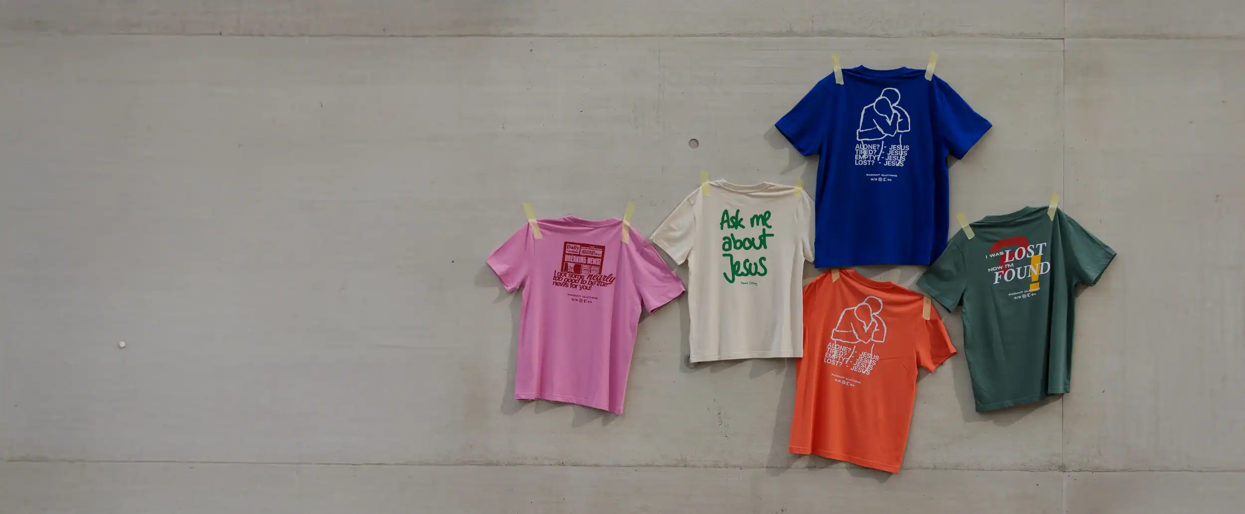 Modische christliche T-Shirts an einer Betonwand zum Verkauf bei stage2603.mookho.de.