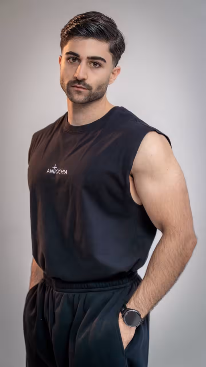 Mann in schwarzem T-Shirt mit "Antiochia" Schriftzug, christliche Mode, Glaube tragen.