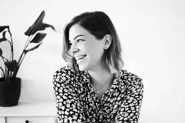 Fröhliche junge Frau mit Blumenmuster-Hemd, lächelnd, natürlicher Look.