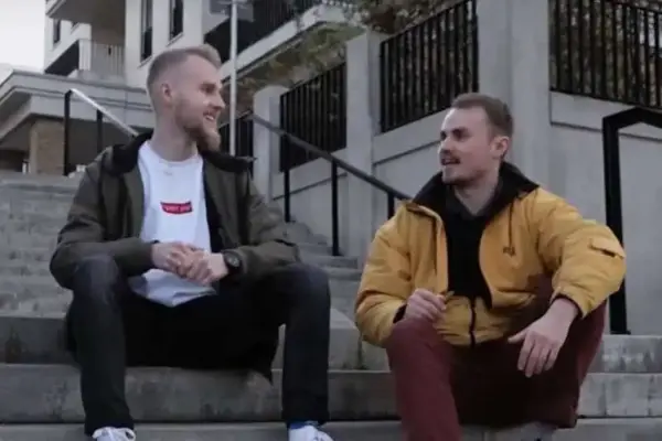 Freundliche junge Männer unterhalten sich auf Straßenstufen in urbaner Umgebung.