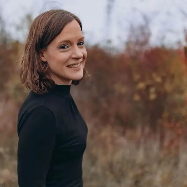 Fröhliche Frau im Herbstlaub, Naturfotografie, Lifestyle, authentisch, warmes Licht.