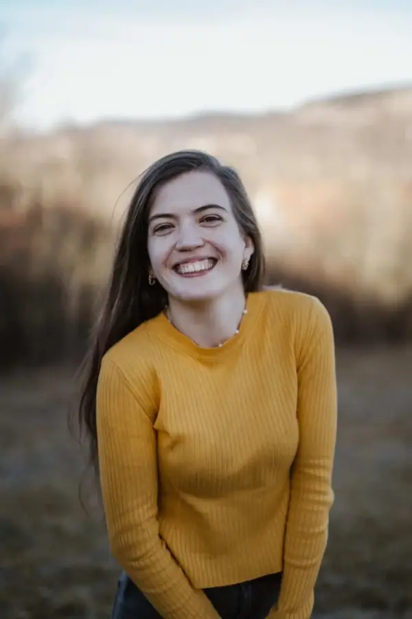 Ein fröhliches junges Mädchen in gelbem Pullover lächelnd im Freien, christliche Gemeinschaft, posit.